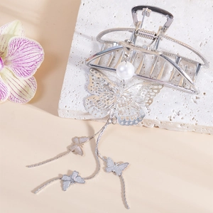 Detail of silver butterfly hair claw with hanging pearls and delicate metal tassels