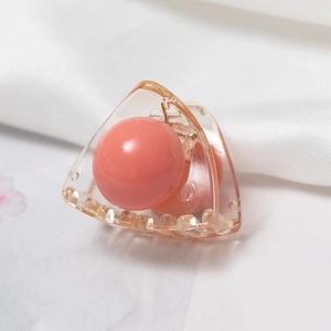 Primer plano de pinza para el cabello naranja translúcida con perla rosa sobre tela