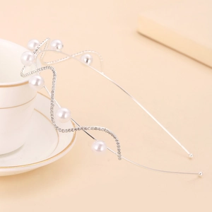 Elegant pearl and rhinestone wavy silver headband on a stylish teacup display