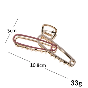 Detail view of large gold claw clip with pink and beige enamel, size 10.8cm by 5cm