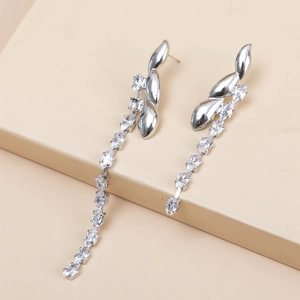 Detail view of silver tassel earrings with marquise-cut zircon stones on a beige platform