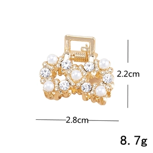 Detalle de una mini pinza para el pelo dorada con perlas y pedrería de 2,8cm