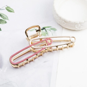 Detail view of large metal hair claw clip with safety pin design in pink and white