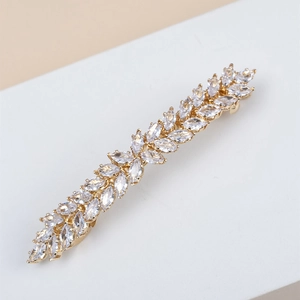 Elegant gold leaf hair clip with marquise-cut crystals for women, side view on white desk
