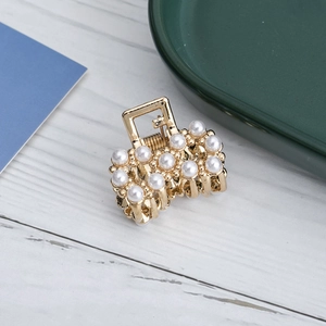 Primer plano detallado de pinza para el cabello en metal dorado con elegantes perlas blancas