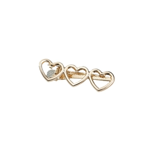 Golden alloy hair clip featuring three hollow heart shapes on a clean white background