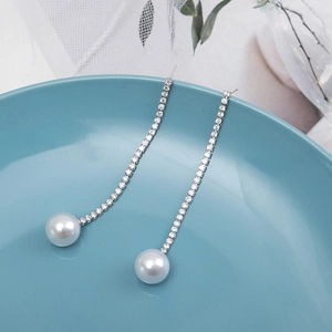 Elegant long tassel earrings with sparkling rhinestones and pearls on a deep blue tray