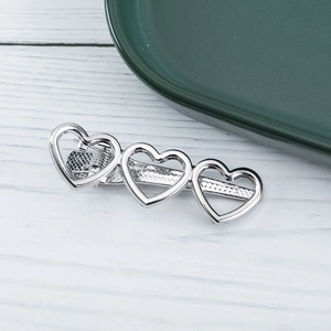 Detail view of silver hollow heart-shaped hair clip with durable spring mechanism