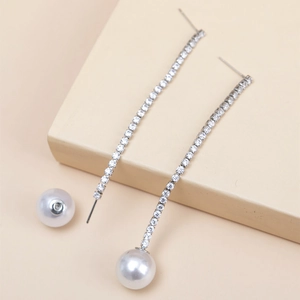 Close-up of long silver tassel earrings with crystal rhinestones and large white pearls