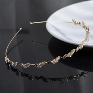 Elegante cerchietto dorato con foglie di opale e fiori di cristallo su fondo a specchio