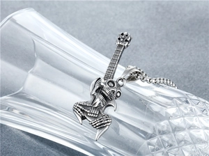 Macro detail of gothic skull electric guitar pendant on steel chain over a glass