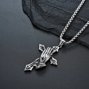 Vintage stainless steel cross necklace with praying hands pendant on dark rock