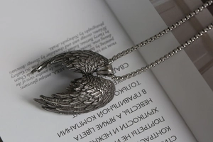 Détail du pendentif ailes d'ange vintage en argent posé sur un livre ouvert