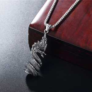 Vintage stainless steel dragon pendant necklace with detailed scales on a wooden box