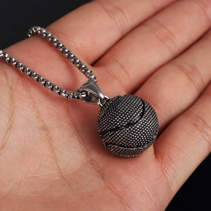 Close-up of a silver basketball pendant necklace with detailed grain texture on a box chain