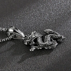 Macro shot of detailed stainless steel dragon pendant on a vintage box chain necklace