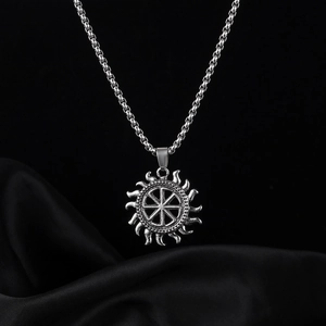Macro shot of silver Slavonic sun wheel pendant on a black silk background