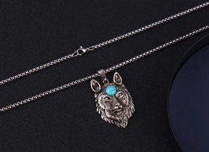 Détail du pendentif tête de loup argentée vintage avec pierre bleue et chaîne acier