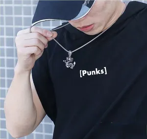 Detailed view of punk silver dragon pendant necklace worn by male model on black t-shirt