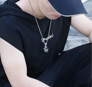Detail of silver dragon pendant necklace in punk style worn on a black hoodie for men