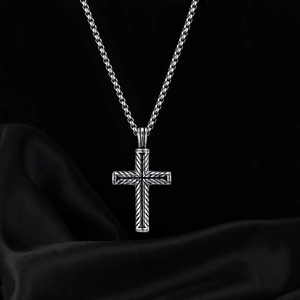 Vintage stainless steel cross necklace with engraved geometric patterns on black silk background