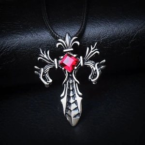 Collana croce gotica in argento con ciondolo gemma rossa su sfondo pelle nera
