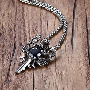 Macro shot of punk style double dragon cross pendant with black gem on aged wood