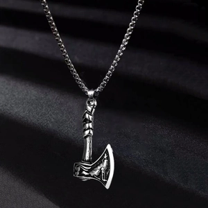 Detail of vintage silver Viking axe pendant with intricate Nordic engravings on box chain