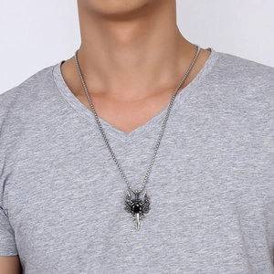 Macro detail of gothic dragon sword necklace with a black gemstone on male model