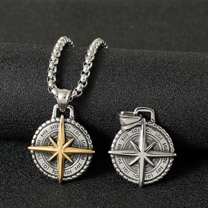 Macro detail of vintage stainless steel compass pendant with golden star on box chain