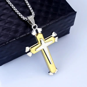 Macro view of triple-layered cross pendant in gold and silver stainless steel finish