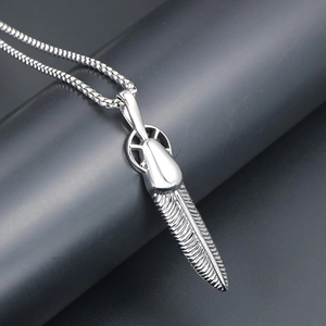 Macro detail of a silver feather pendant with detailed wings on a titanium box chain