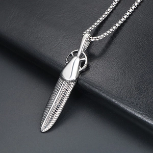 Macro shot of silver feather pendant with detailed texture on a black box chain necklace