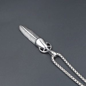Macro detail of silver feather pendant with intricate textures and box chain necklace