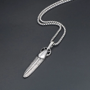 Detailed close-up of retro silver feather pendant with cross wheel on pearl chain