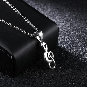 Détail du collier pendentif clé de sol en argent poli sur un présentoir noir texturé