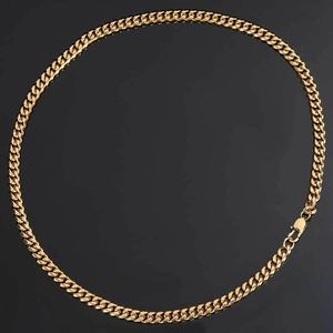 Detailed view of heavy gold-plated Cuban link chain with lobster clasp on black background