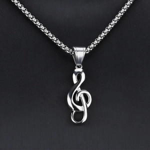 Détail macro du pendentif note de musique G-clef en acier poli sur chaîne à billes