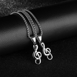 Détail de colliers clé de sol en argent présentés sur un support en cuir noir élégant