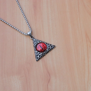 Vue détaillée du collier pendentif œil de dragon argenté sur un fond en bois clair