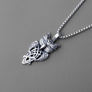 Détail du pendentif hibou viking rétro avec nœud celtique sur fond en cuir gris texturé