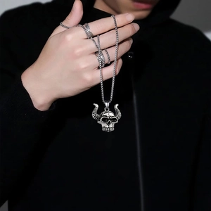 Detailed view of punk style silver ox skull pendant necklace held in hand with jewelry