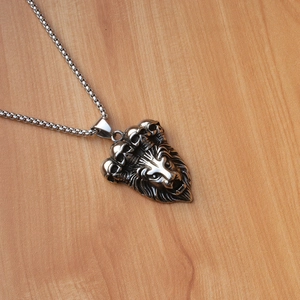 Detalle del colgante de cabeza de león punk con calaveras en una cadena de plata antigua
