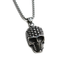 Détail d'un pendentif tête de mort punk avec clous pyramides et chaîne en acier robuste