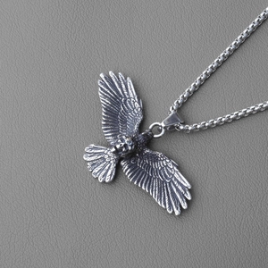 Detailed close-up of gothic stainless steel eagle pendant with skull and box chain
