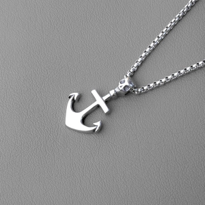 Detailed macro shot of stainless steel anchor pendant with skull motif on box chain