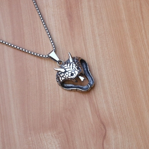 Macro detail of a silver cobra snake pendant with horn decor on a stainless steel box chain