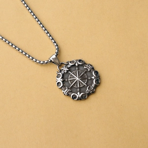 Dettaglio di un ciondolo bussola vintage in argento antico con catena a maglia box