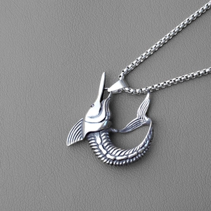 Macro view of vintage silver swordfish pendant with detailed fins on box chain