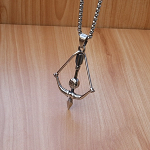 Close-up of silver bow and arrow pendant with floral emblem on a sturdy box chain